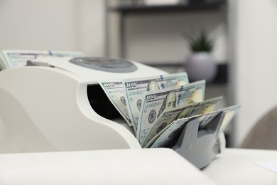 Photo of Modern banknote counter with money on white table indoors, closeup