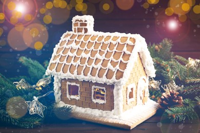 Beautiful gingerbread house decorated with icing and fir branch on wooden table
