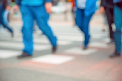 People crossing street outdoors, closeup. Blurred view