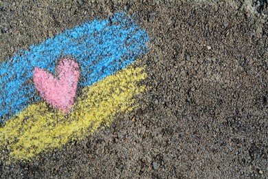 National flag of Ukraine with heart drawn by color chalk on asphalt, top view. Space for text