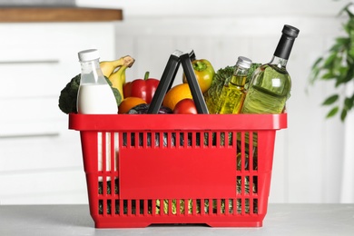 Shopping basket with grocery products on grey table indoors