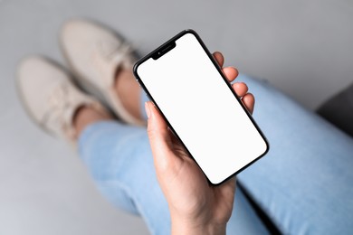 Photo of Woman holding smartphone with blank screen indoors, top view. Mockup for design