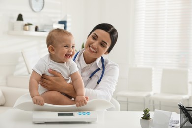 Photo of Young pediatrician weighting cute little baby in clinic. Space for text