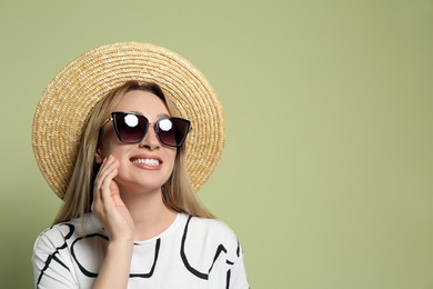 Beautiful young woman wearing straw hat and sunglasses on light green background, space for text. Stylish headdress