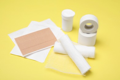White bandage rolls and medical supplies on yellow background