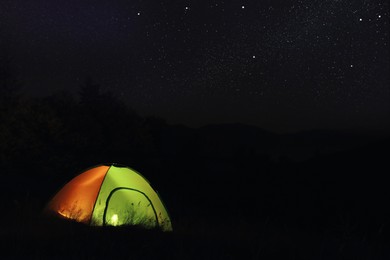 Camping tent glowing at night outdoors. Space for text