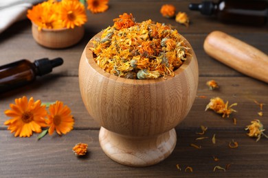 Mortar of dry calendula flowers on wooden table