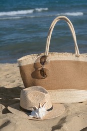 Stylish bag and other beach accessories near sea on sunny day