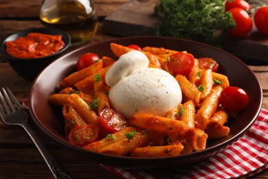 Delicious pasta with burrata cheese and tomatoes on wooden table, closeup