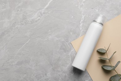Dry shampoo spray and eucalyptus on light grey marble table, flat lay. Space for text
