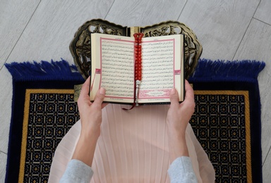 Muslim woman reading Koran indoors, top view