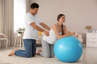 Husband massaging his pregnant wife in light room. Preparation for child birth