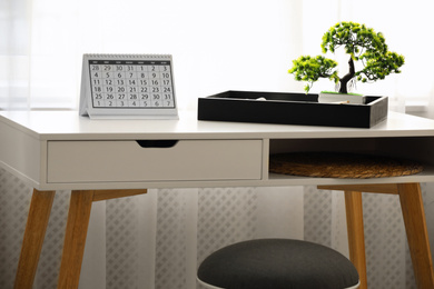 Paper calendar and bonsai tree on white table indoors