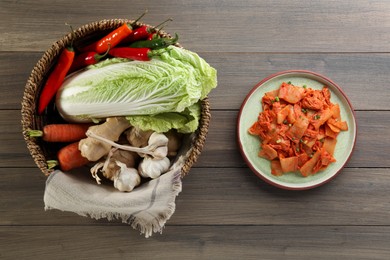 Delicious kimchi with Chinese cabbage and ingredients on wooden table, flat lay