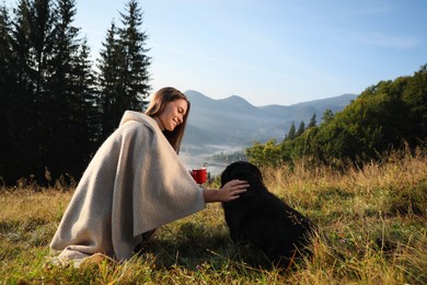 Young woman enjoying time with her dog in mountains