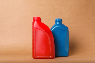 Photo of Motor oil in different canisters on light brown background