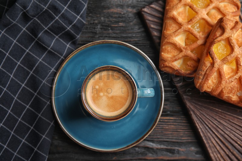 Photo of Delicious coffee and pastries on black wooden table, flat lay