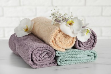 Rolled and folded towels with lilies on white table, closeup