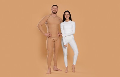 Photo of Man and woman in warm thermal underwear on beige background