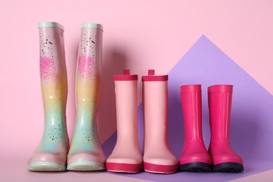 Three pairs of rubber boots on color background