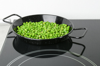 Cooking frozen sweet peas on induction stove. Vegetable preservation