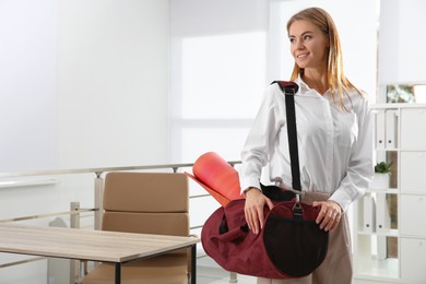 Beautiful businesswoman with sports bag in office