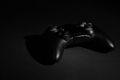 Video game controller on black background, space for text
