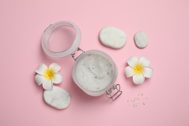 Photo of Body scrub, spa stones and plumeria flowers on pink background