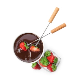 Fondue forks with strawberries in bowl of melted chocolate on white background, top view
