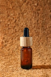 Photo of Bottle of essential oil on brown textured background