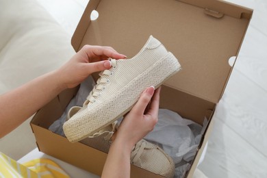Woman with canvas shoes and box on sofa, closeup