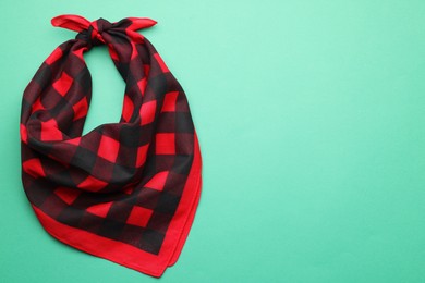 Tied red checkered bandana on turquoise background, top view. Space for text