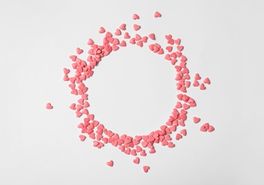Round frame made of pink heart shaped sprinkles on white background, flat lay. Space for text