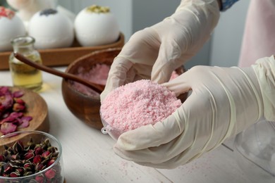 Woman in gloves making bath bomb at white table, closeup