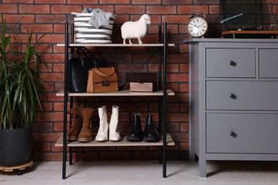 Photo of Beautiful hallway interior with chest of drawers and shoe storage bench near red brick wall