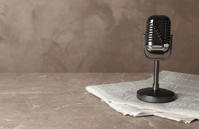 Newspapers and vintage microphone on marble table, space for text. Journalist's work