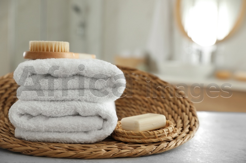 Wicker tray with clean towels on table in bathroom