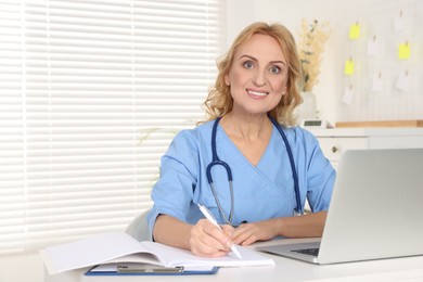 Portrait of doctor with laptop at workplace in clinic. Online medicine concept