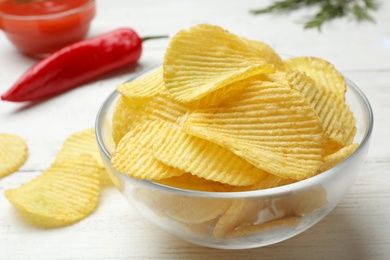 Delicious crispy potato chips in bowl on table, closeup