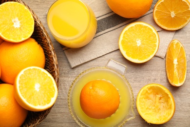 Squeezer, fresh oranges and juice on wooden table, flat lay