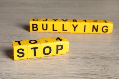 Phrase Stop Bullying made of yellow cubes with letters on wooden table, closeup