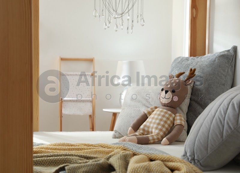 Comfortable wooden house bed with cushions and toy in child room. Interior design