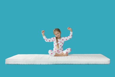 Photo of Little girl waking up on mattress against light blue background