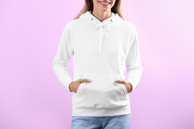 Photo of Woman in hoodie sweater on color background. Space for design
