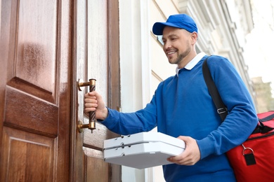 Male courier with order at entrance. Food delivery service