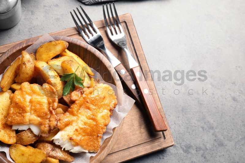 Wooden plate with British traditional fish and potato chips on table. Space for text