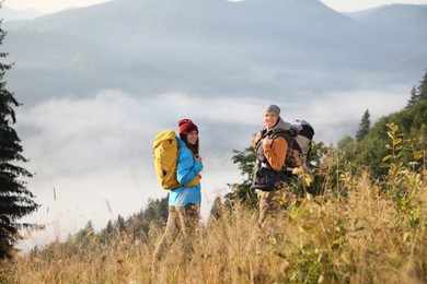Tourists with backpacks hiking in foggy mountains