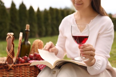 Woman with glass of wine having picnic in park, closeup