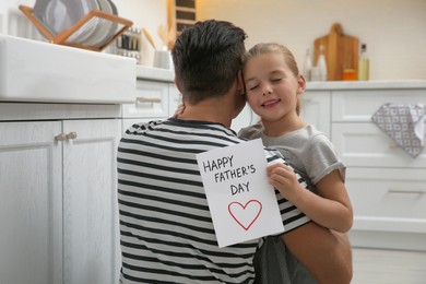 Little girl greeting her dad with Father's Day in kitchen
