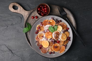 Cereal pancakes with cranberries served on black table, top view